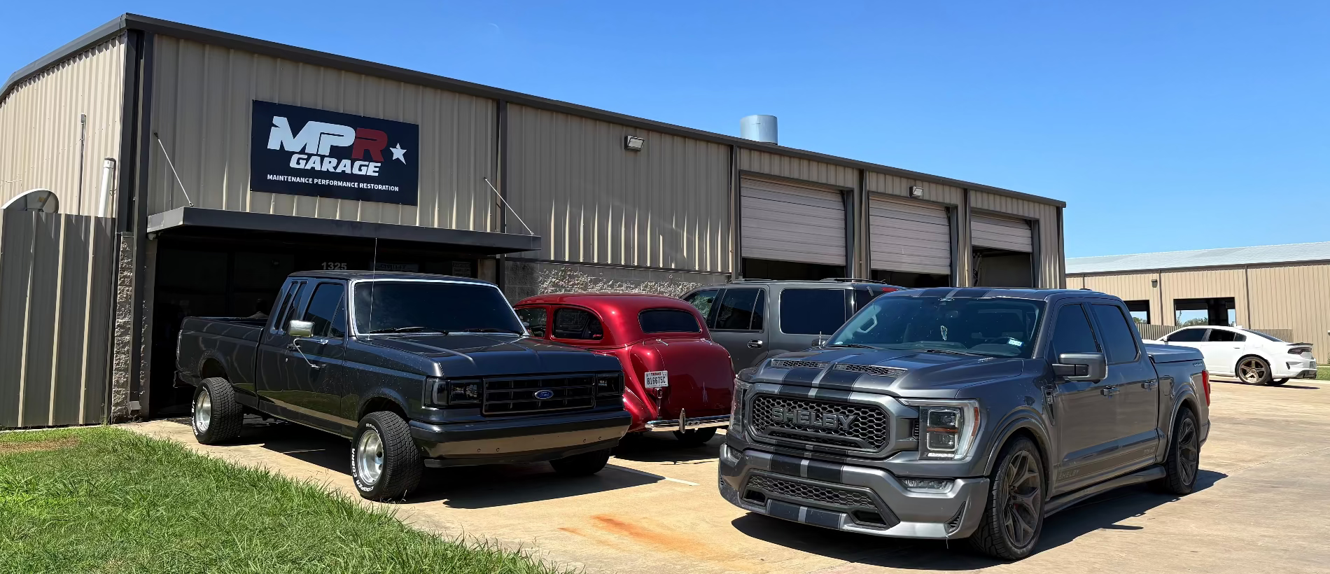 Two pickup trucks parked outside a building with a sign that reads 'MP Garage'.